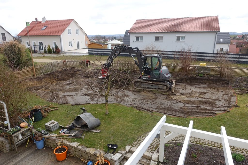Baubeginn für Schwimmteich Selbstbau mit Bagger und Baum im Garten