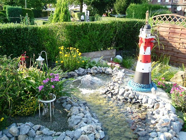 Wasserquelle mit kleinem Wasserspiel an einem Leuchtturm gebaut aus vielen kleinen Natursteinen