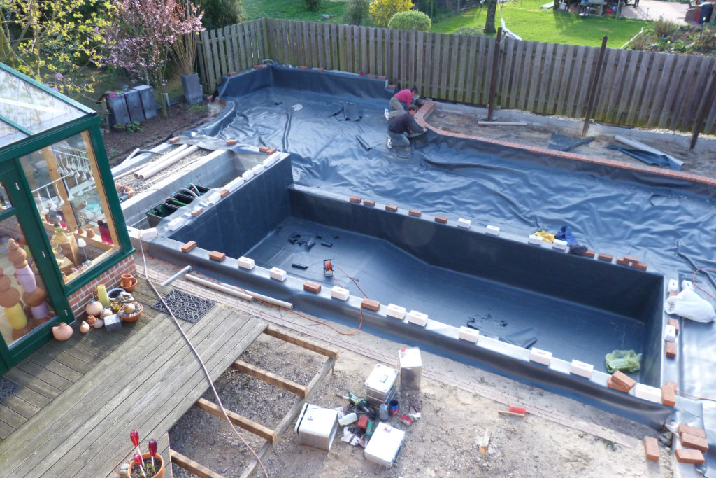 Mitarbeiter verschweißen die Folie am äußeren Rand des Pflanzbereichs im Schwimmteichprojekt.