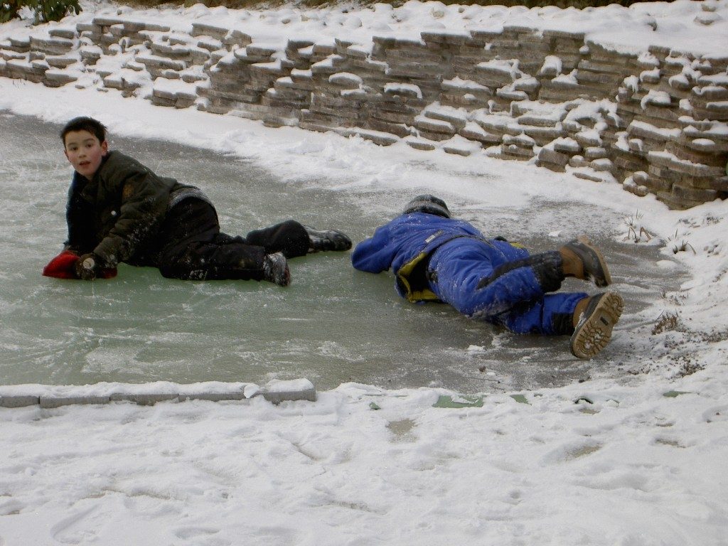 Schlitterspaß auf zugefrorenem Teich