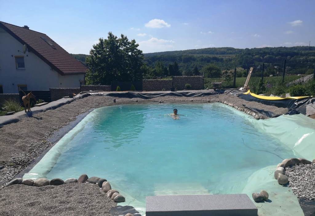 Steine sind zwischen Pflanz- und Schwimmbereich platziert, um das Verrutschen von Kies zu verhindern. Das erste mal Baden im eigenen Schwimmteich.