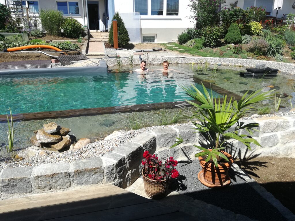 Menschen im Schwimmbereich mit Pflanzen und Wasser – Genuss und Entspannung im eigenen Schwimmteich.