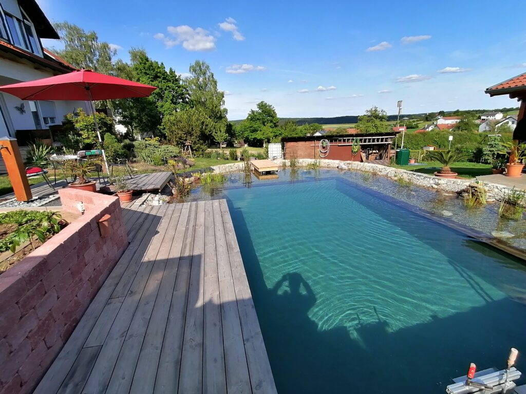 Steg, Holzterrasse und Regenerationszone – Einladende Bereiche rund um den Schwimmteich.