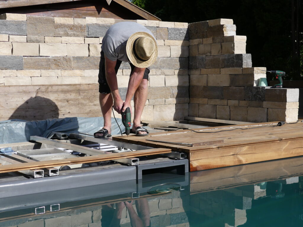 Eine Unterkonstruktion wurde neben und über den Technikschacht gebaut. Holzbretter werden auf der Konstruktion verschraubt.