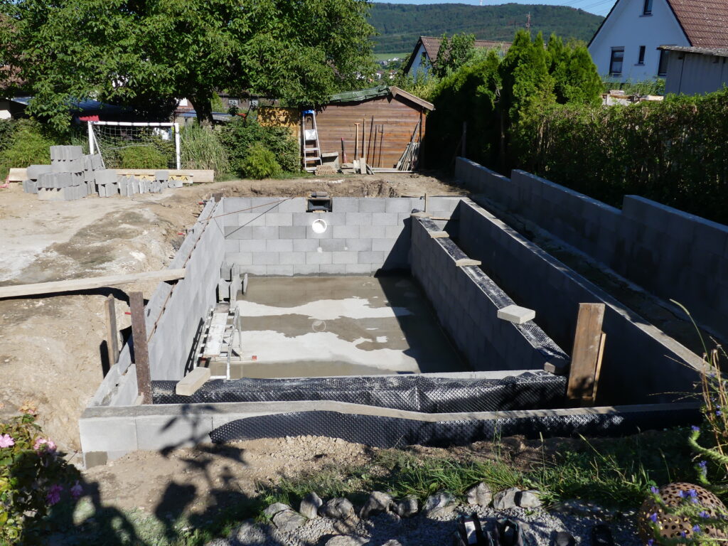 Bau der Filterzone mit Schalungssteinen, Gartenmauer, Skimmer und Mauern des Schwimmbereichs.