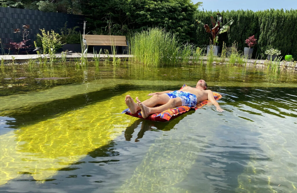 Klares Wasser im Schwimmteich mit üppiger Wasserpflanzenwelt. Auf der Luftmatratze im Schwimmteich lässt es sich gut entspannen