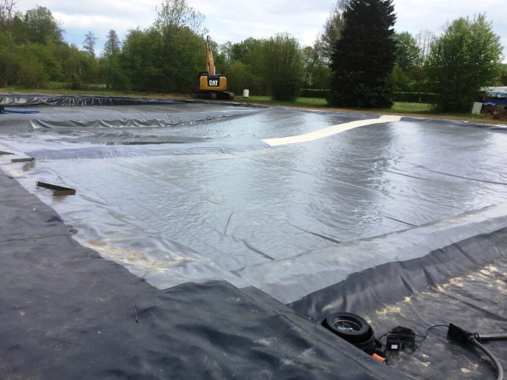 Schwimmteich mit verschweißter Teichfolie. Hier entsteht ein großer Schwimmteich in einem Campingplatz