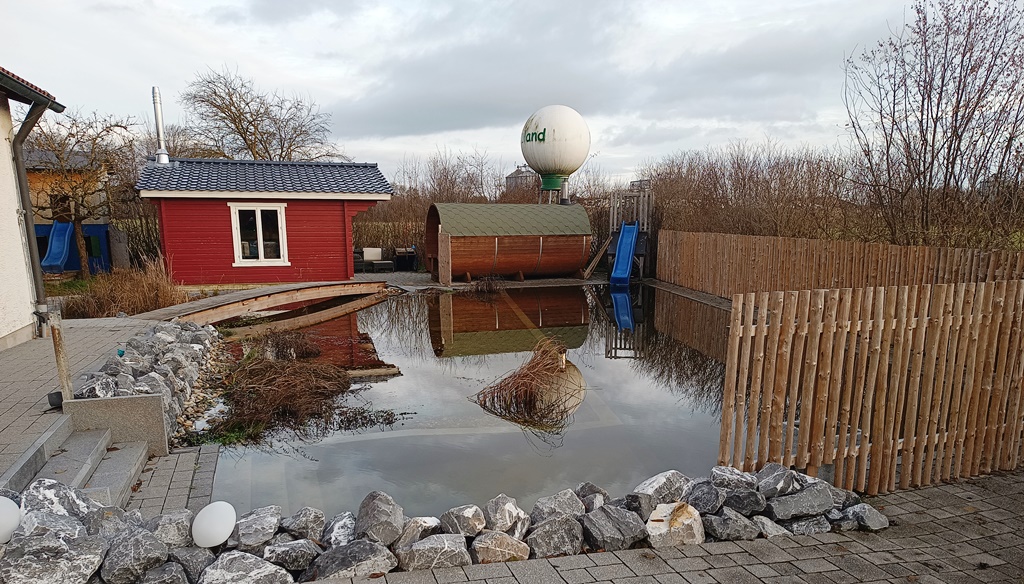 Fertiger Schwimmteich bei Ulm mit einer Fass-Sauna und einer Wasserrutsche