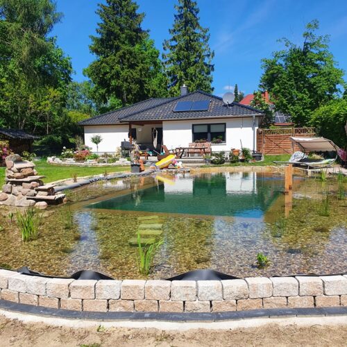 Fertiger Schwimmteich bei Berlin. Mit Terrasse und Steg laden zum Baden ein.