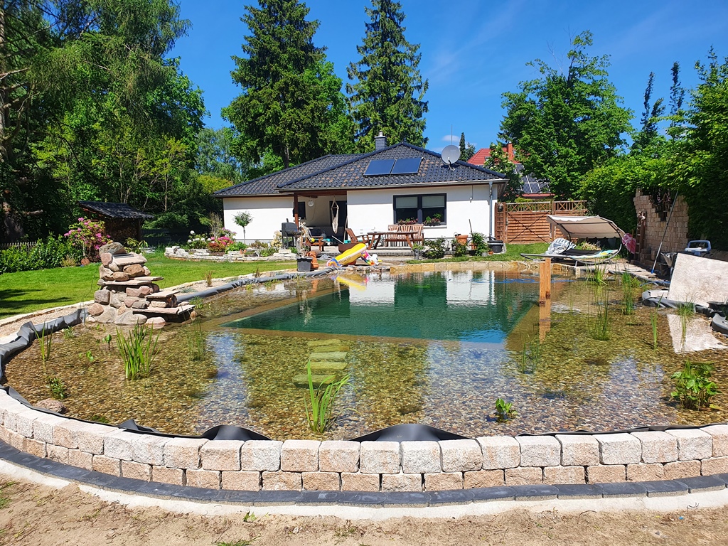 Fertiger Schwimmteich bei Berlin. Mit Terrasse und Steg laden zum Baden ein.