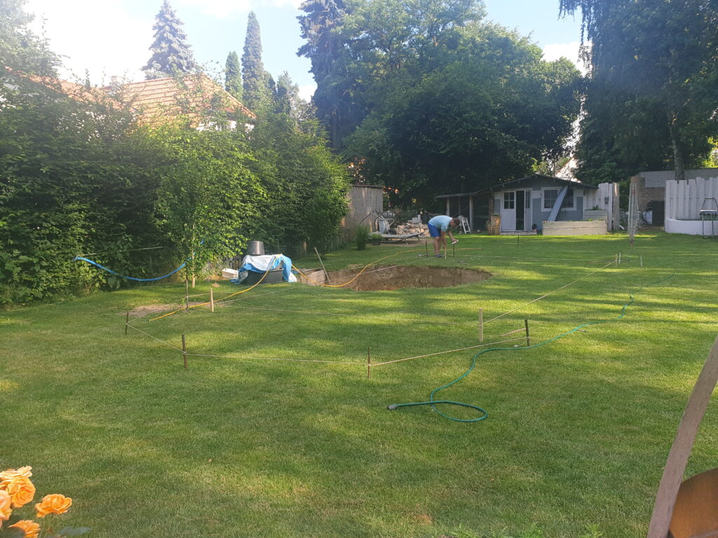 Ein Garten wird mit Seil und Pflöcken abgesteckt. Hier entsteht ein Schwimmteich.